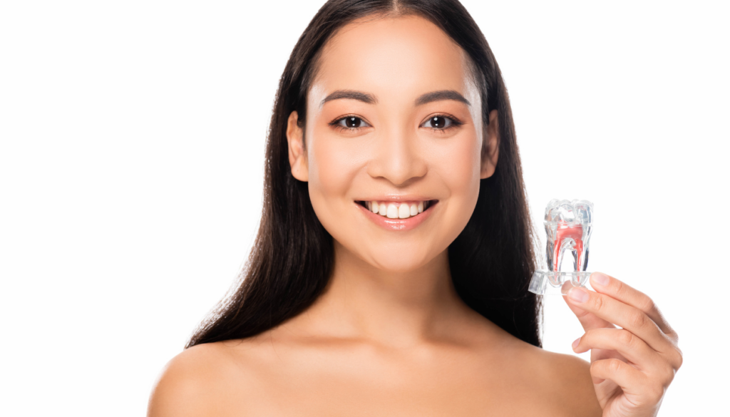 Woman holding clear aligners, smiling towards the camera, featured in the top orthodontic options blog.