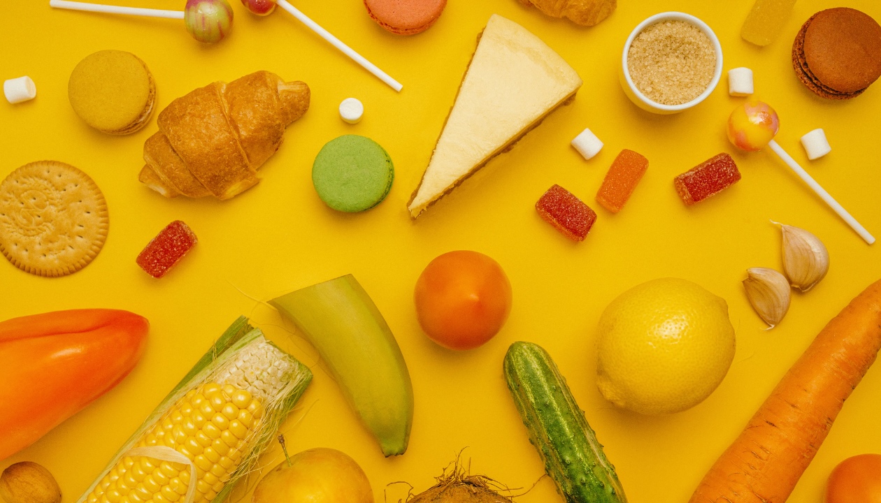 Various fruits, vegetables, and cheeses on an orange background, featured in the braces care blog post.