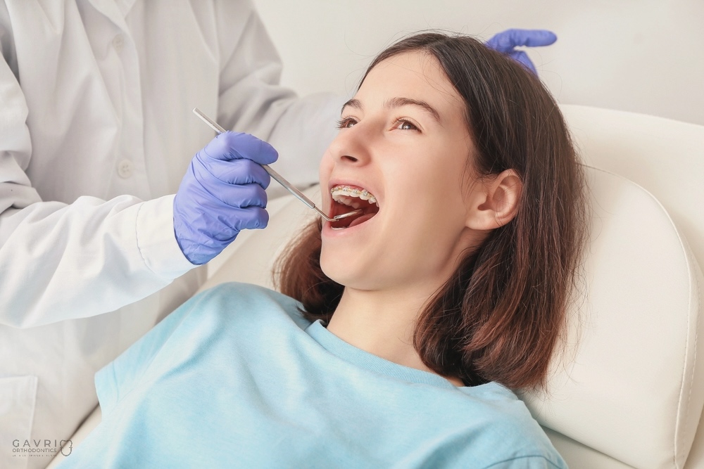 Teenage girl smiling during orthodontic checkup with braces.